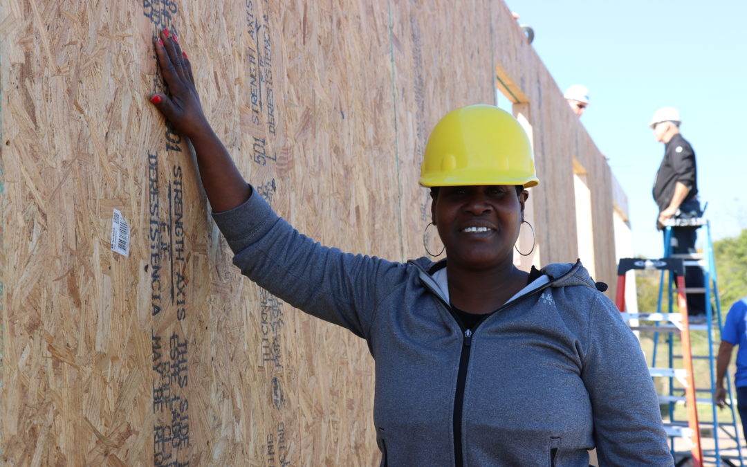 A Habitat Orlando & Osceola volunteer leans on the wall of a home that's under construction.