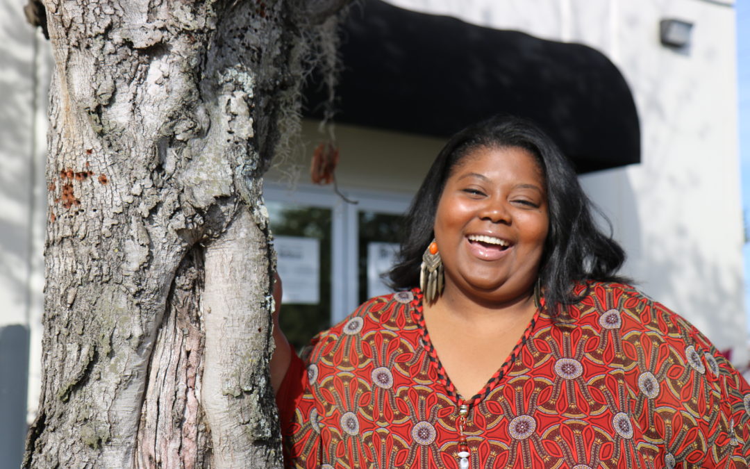 Woman laughing next to a tree in front of Habitat Orlando & Osceola headquarters