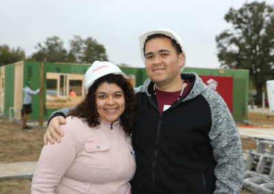 Man and woman smiling and standing in front of in-progress house