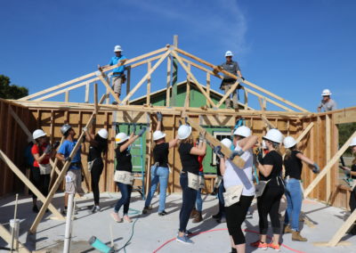 Group of women holding wooden beams to raise trusses