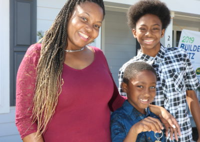 Woman and two young boys in front of completed home