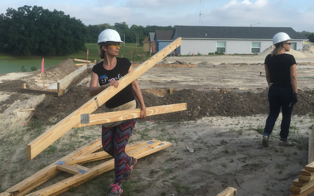 Woman wearing goggles and hard hat, carrying trusses