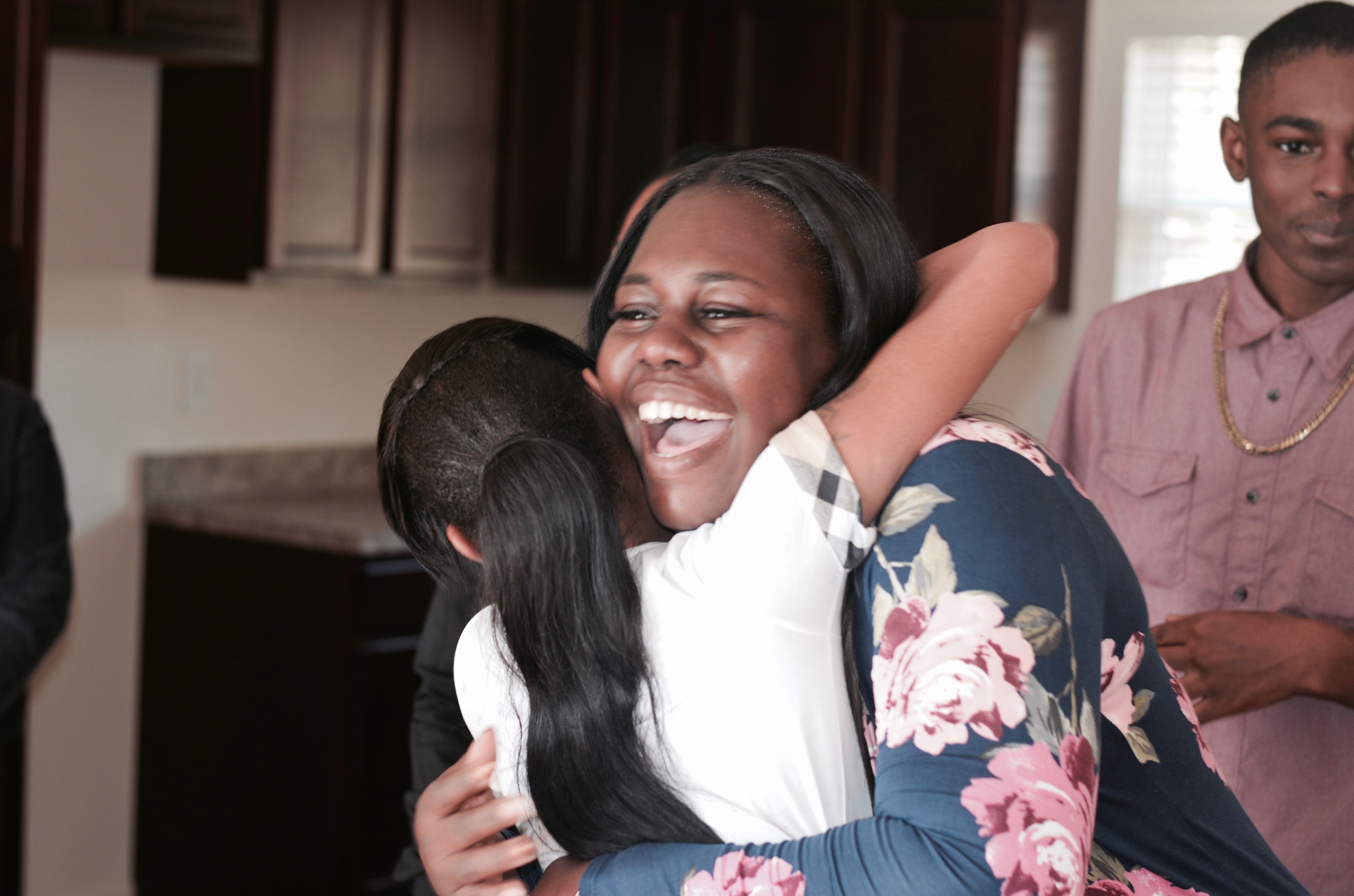Mulheres sorrindo e abraçando outra mulher em sua cozinha novinha em folha