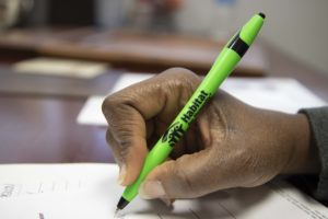 Primer plano de una mano sujetando un bolígrafo y escribiendo en un papel