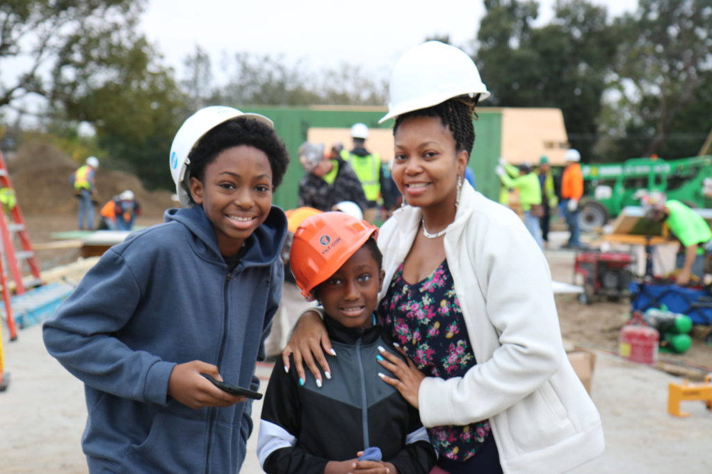 Homeowner Patricia and her two sons pose in hard hats in front of their home, which was under construction. 