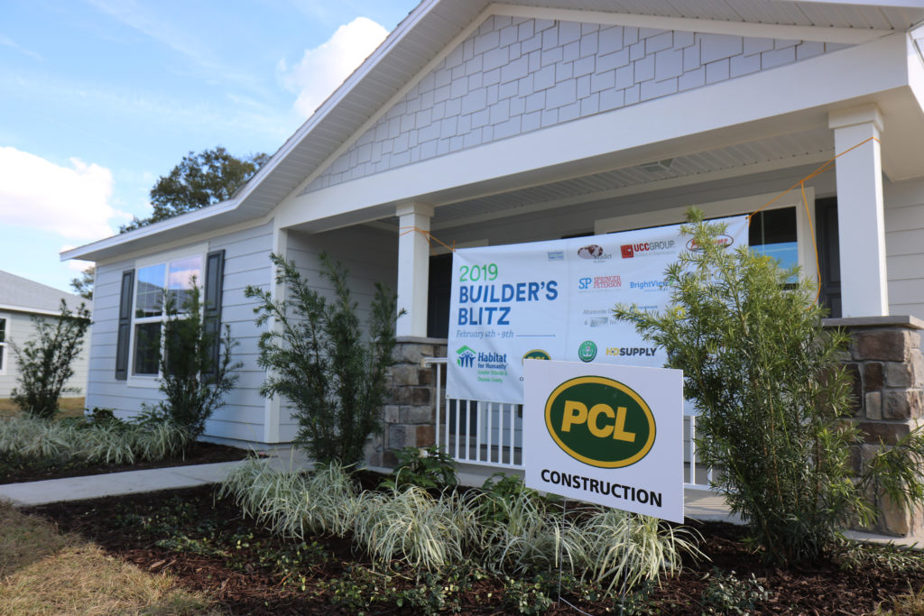 Una foto de la casa de Patricia en Arbor Bend con un letrero de 2019 Builders Blitz, así como un letrero de PCL Construction en el frente.