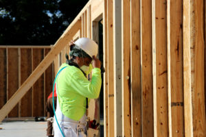 Woman wearing hard hat facing interior unfinished walls of house