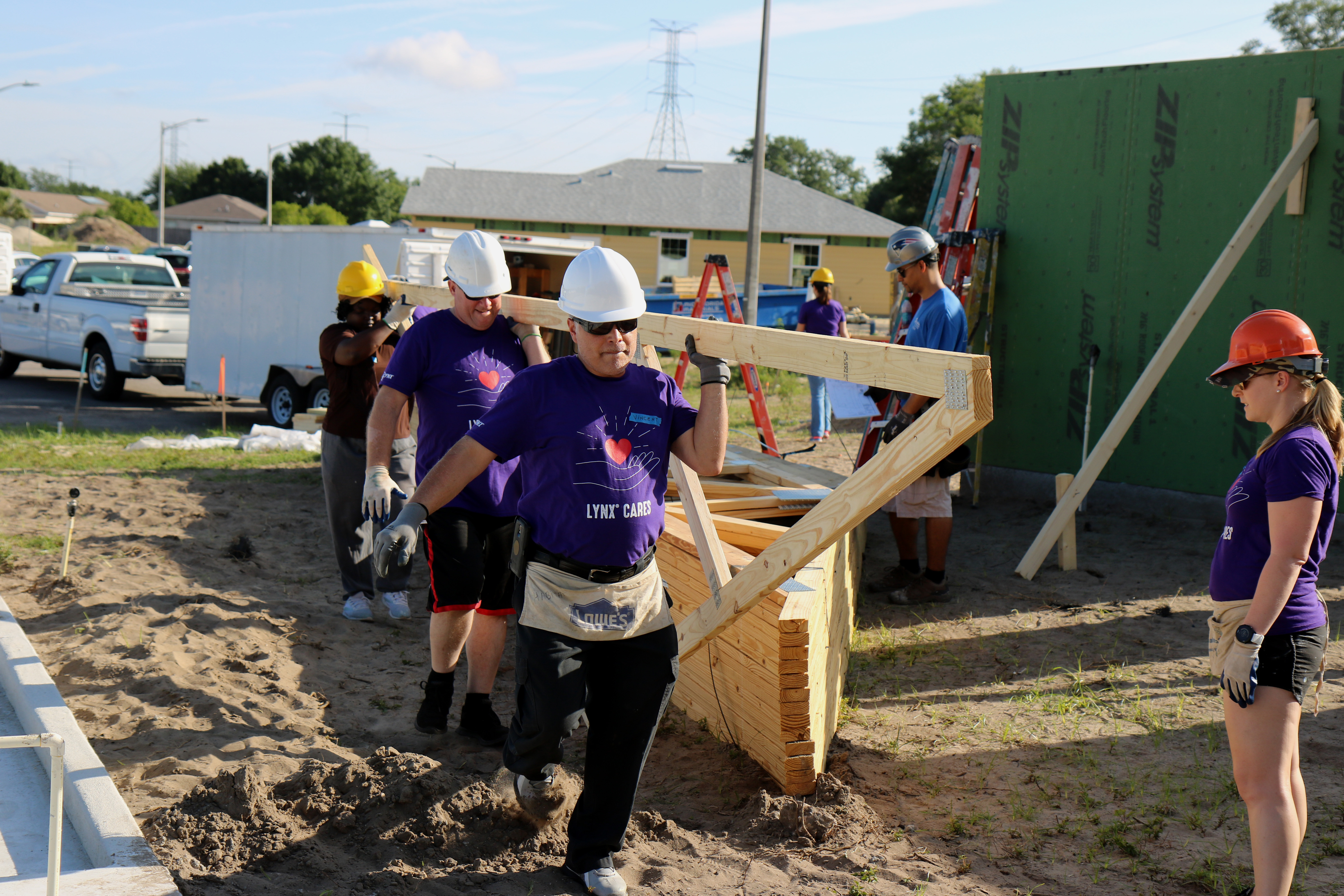 Group of three volunteers carrying trusses on build site