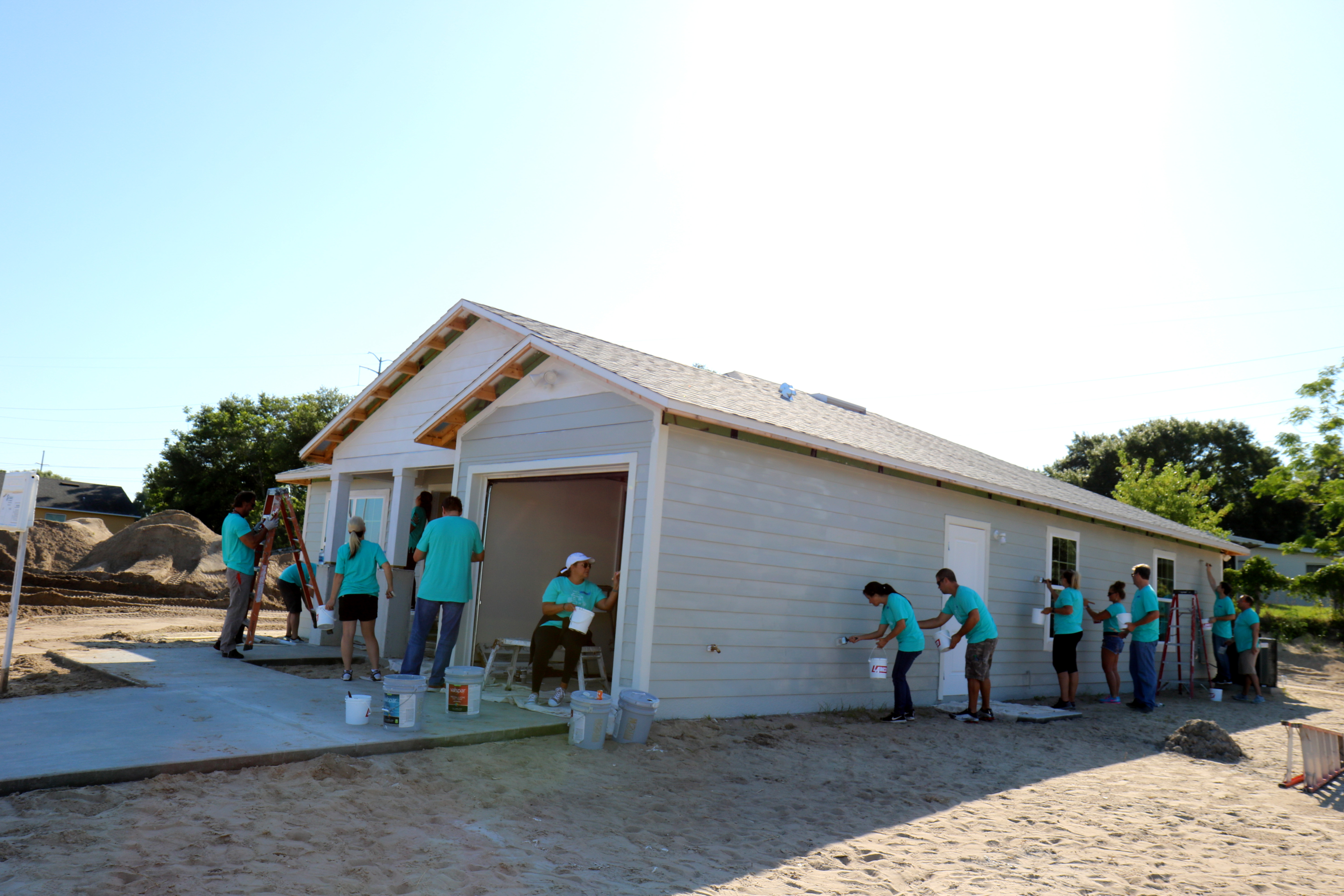 Group of volunteers painting exterior of home