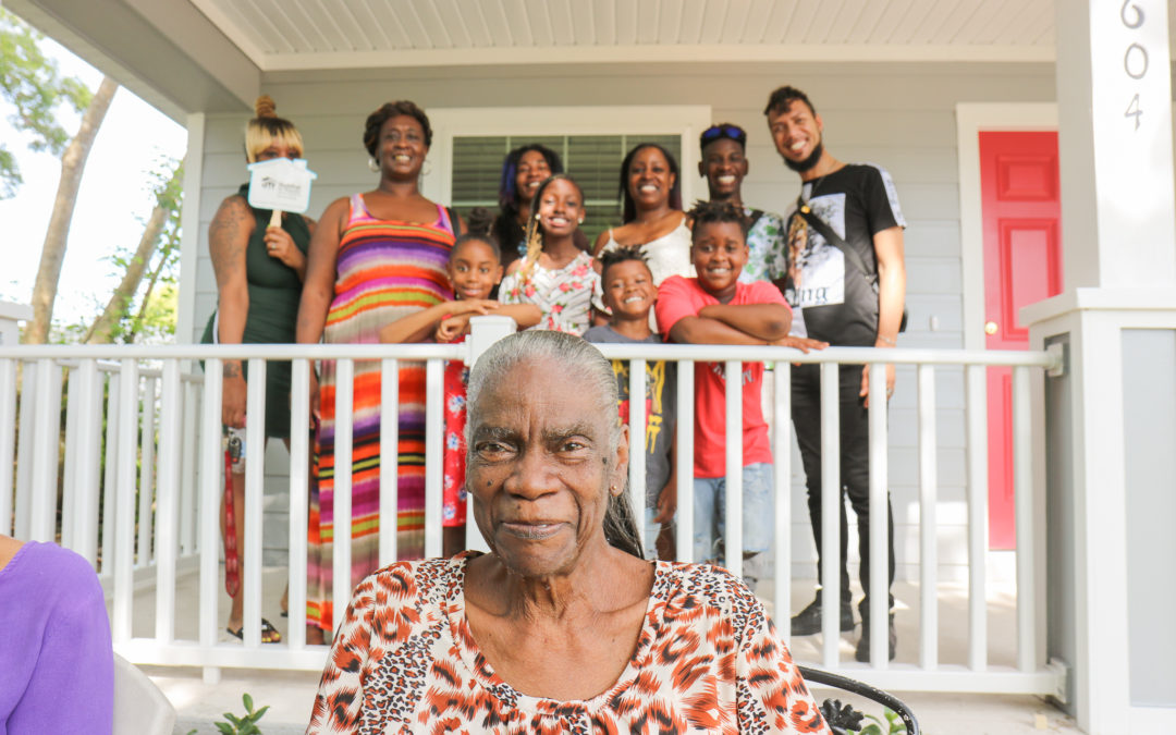 Vivian in front of her rebuilt home, with her family.