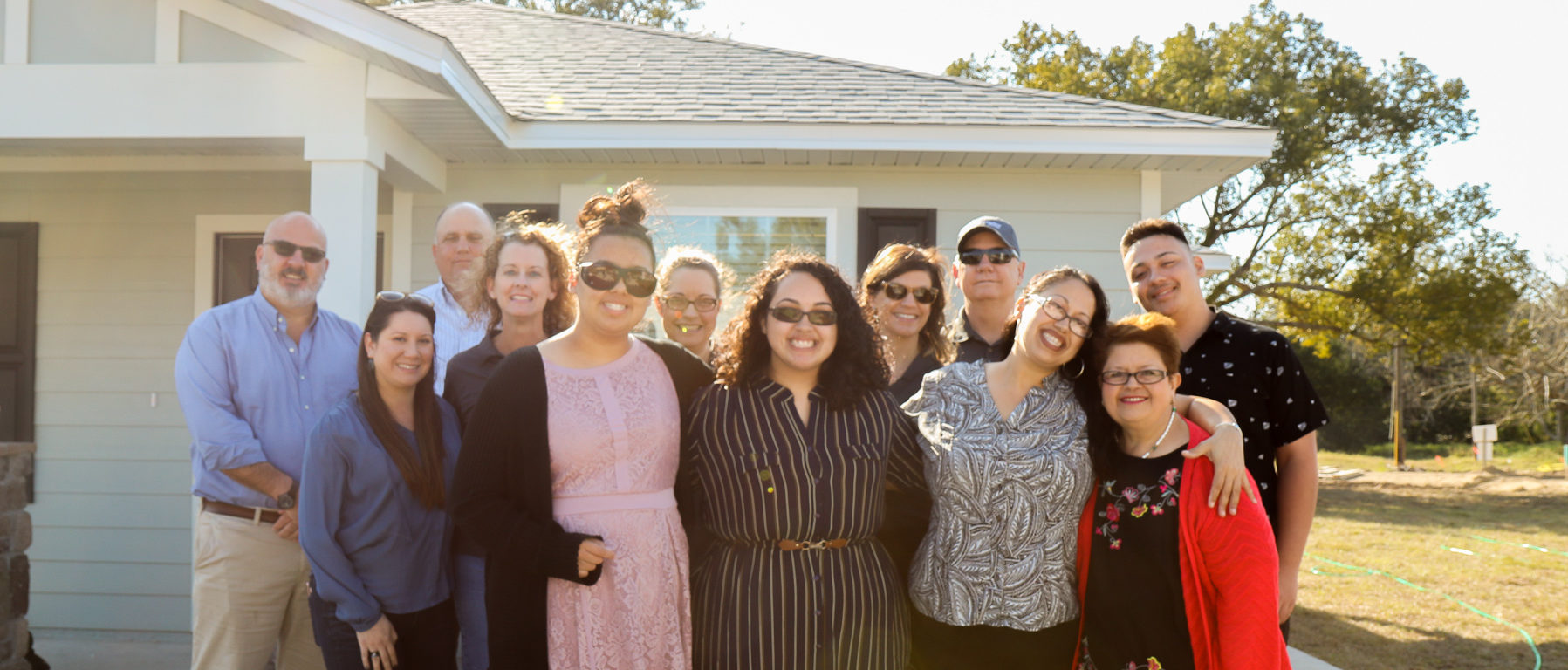 Large group of people with family in front and group of K. Hovnanian team members behind them, all in standing in front of newly completed house