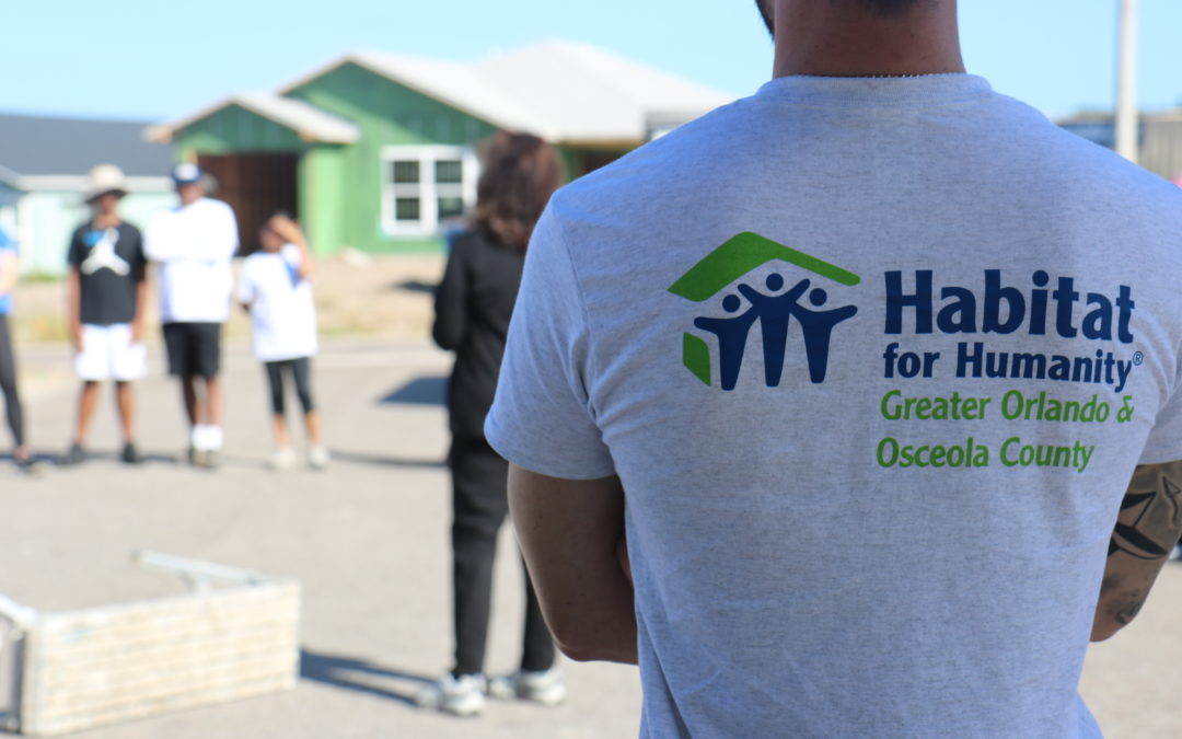 A volunteer in a Habitat Orlando & Osceola T-shirt looks out into a construction site.