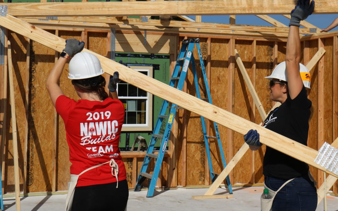 two women carrying trusses in in-progress house