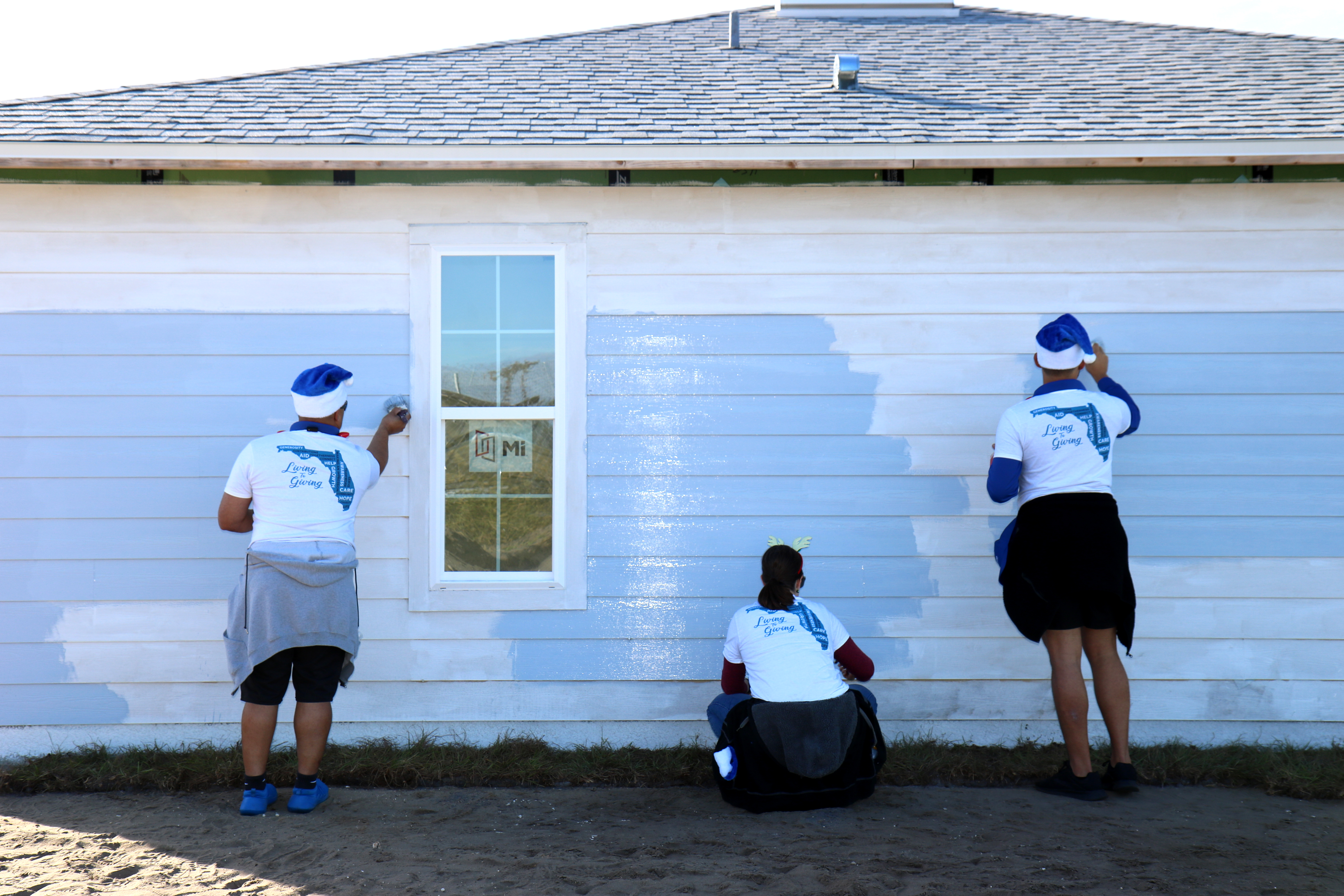 Three volunteers paint a house.