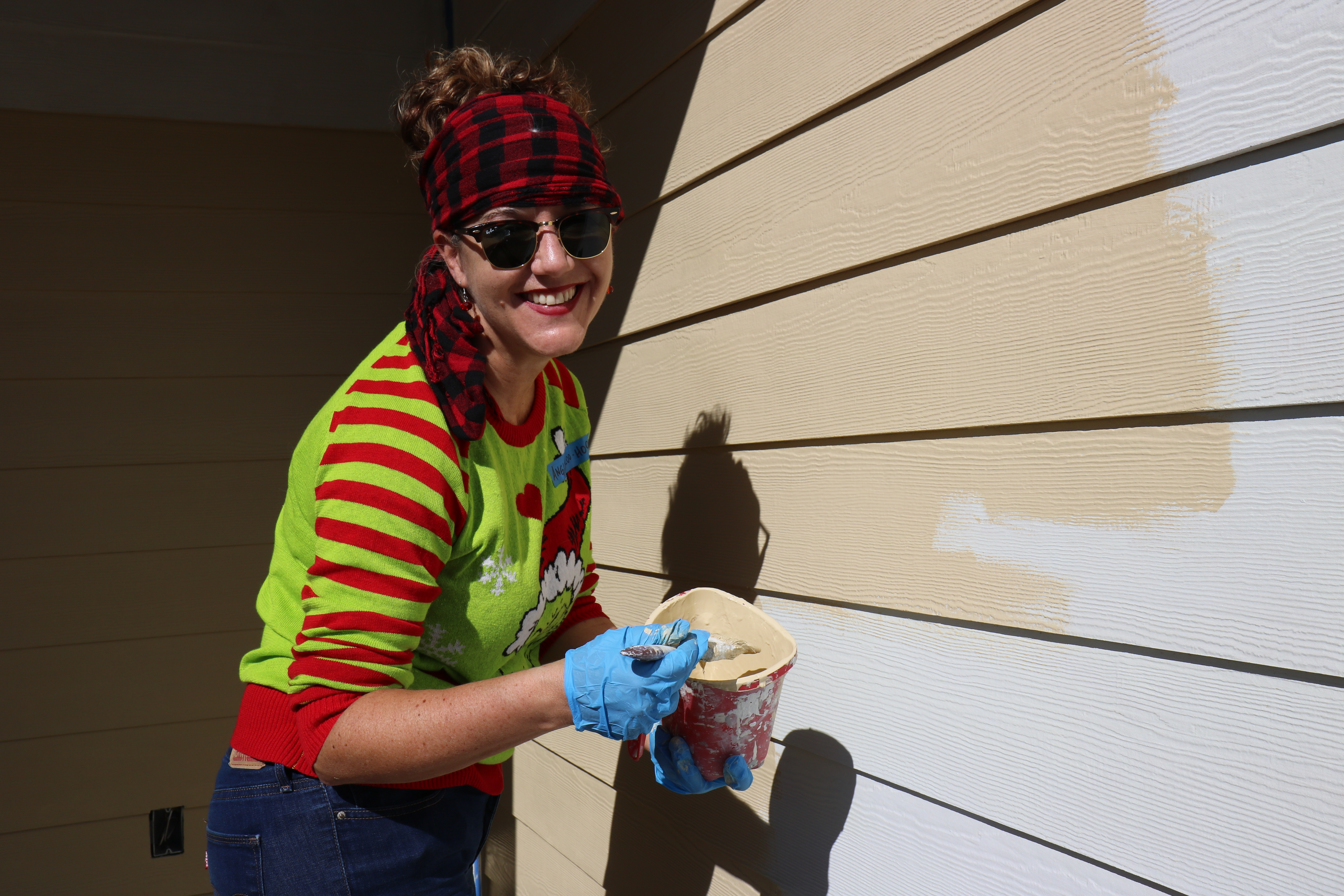 A volunteer poses while painting a house.