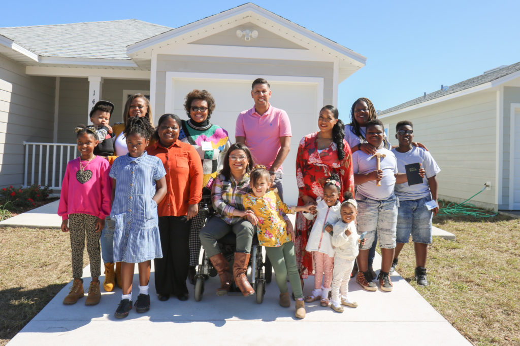 A group of people stand in front of a house.