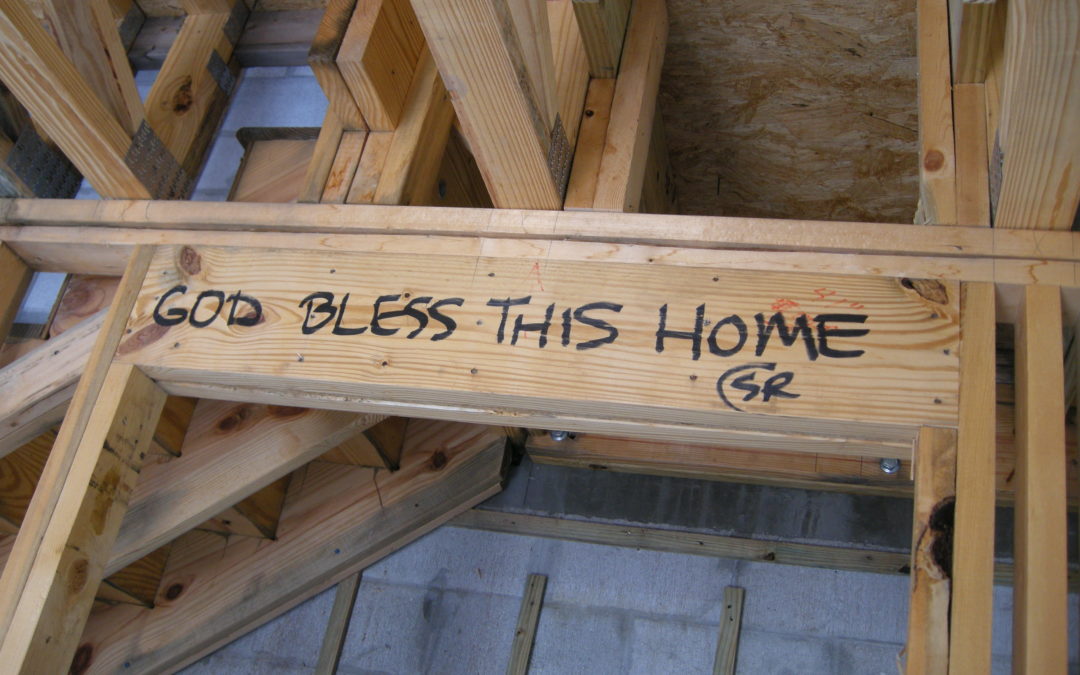 "God Bless This Home" is written on the boards of a house.