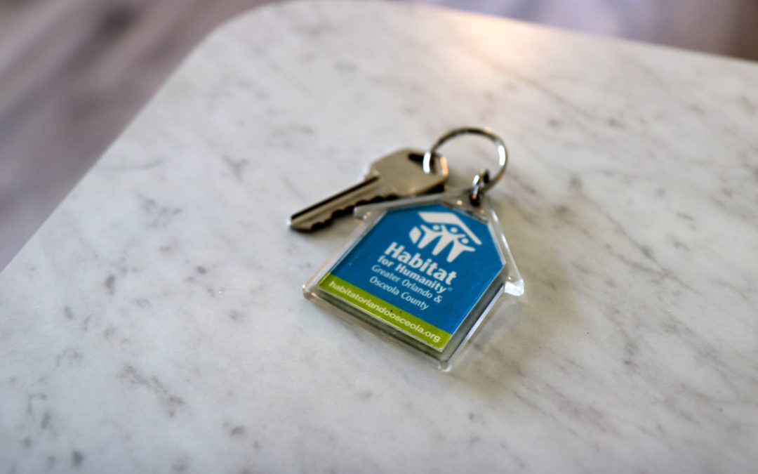 A key on a Habitat keychain sits on a white countertop.