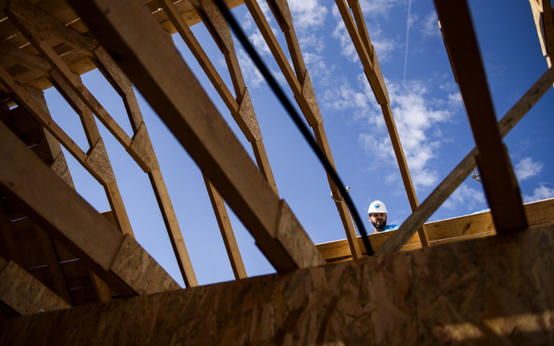 A man peeks over the top of a wall in a house that is under construction.