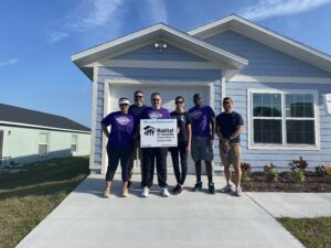 A team from Universal Orlando poses in front of a house with a Habitat sign.