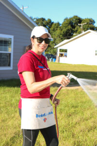 A Bank of America volunteer waters a Habitat home's lawn.