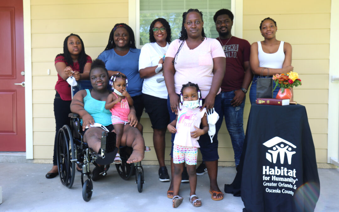 A family poses in front of their home