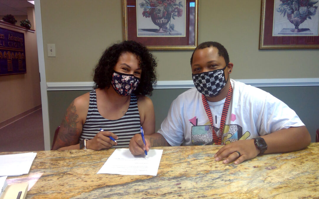 A woman and a man sign a document.