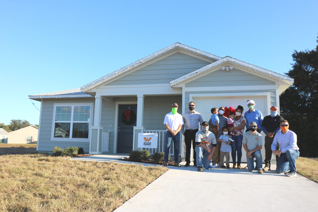 La familia Bogan, representantes de Williams Company y miembros del personal de Habitat posan delante de una casa de Habitat.