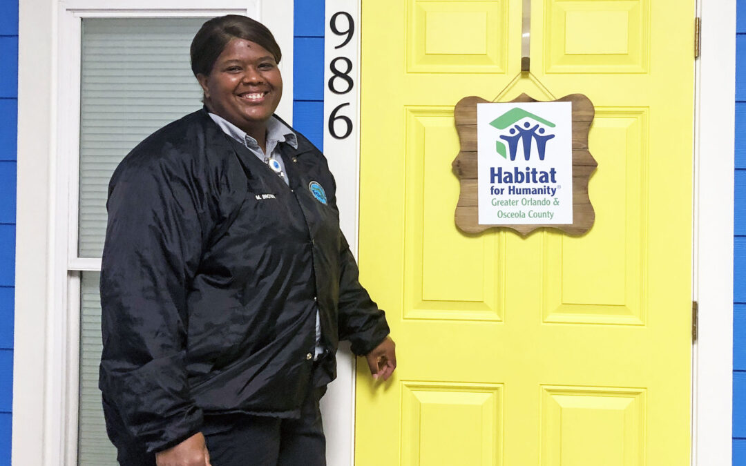 Mulher sorridente posa com modelo de casa Habitat