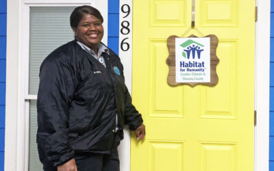 Smiling woman poses with Habitat house model