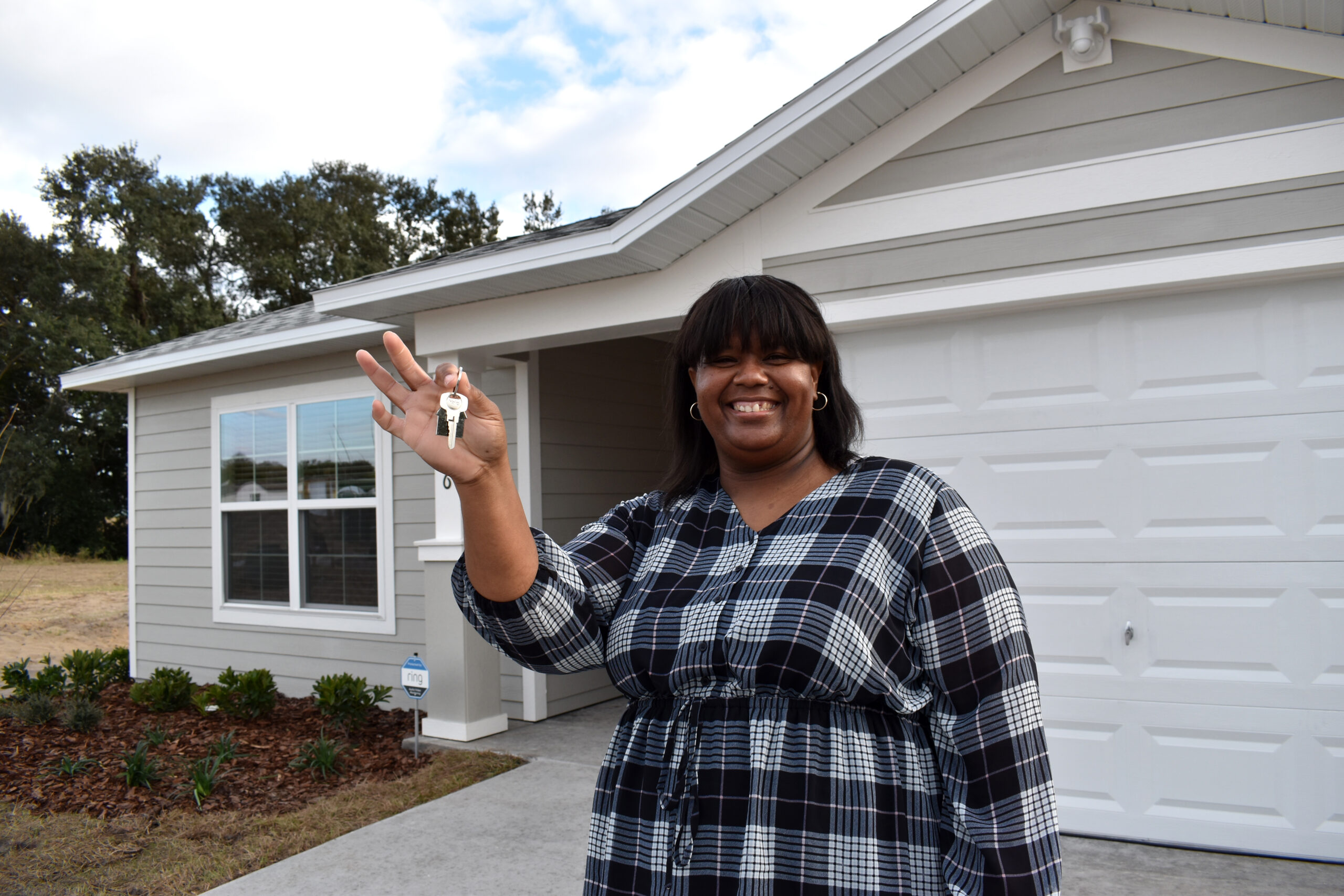 Park Square Blitz 2023 A smiling woman holds up her keys in front of her home.