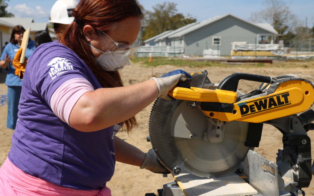 Woman using a power saw to cut a board