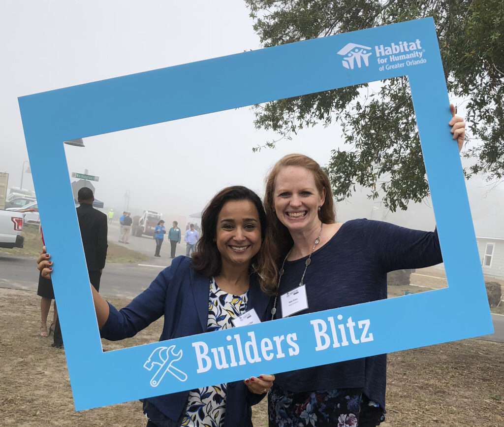 Two women smile in a giant frame