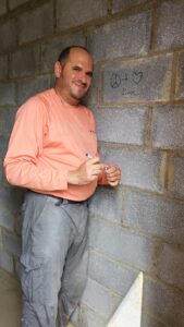 Volunteer coordinator David Bunzel poses next to a message he wrote on a concrete wall for a future Habitat homeowner