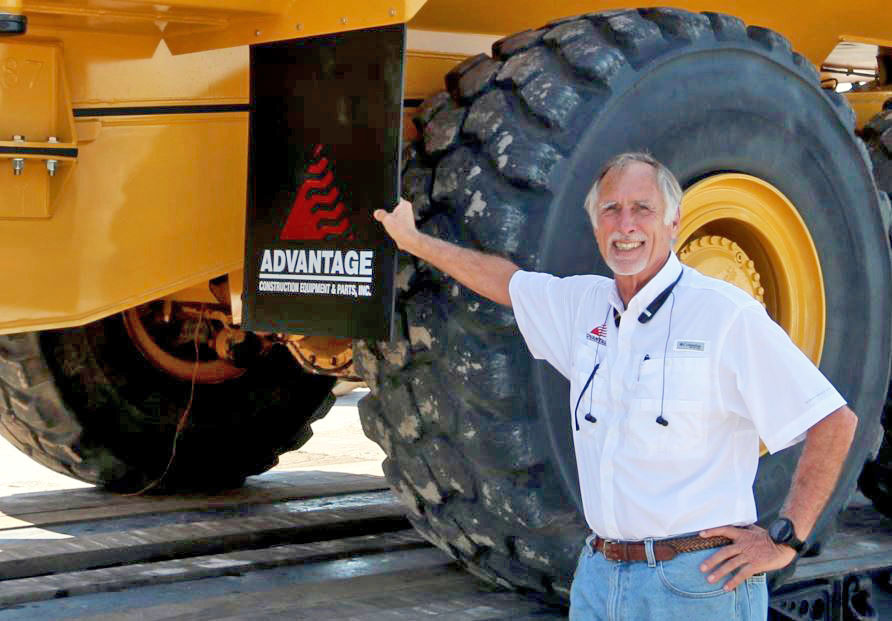 Um homem sorri em frente a um equipamento de construção