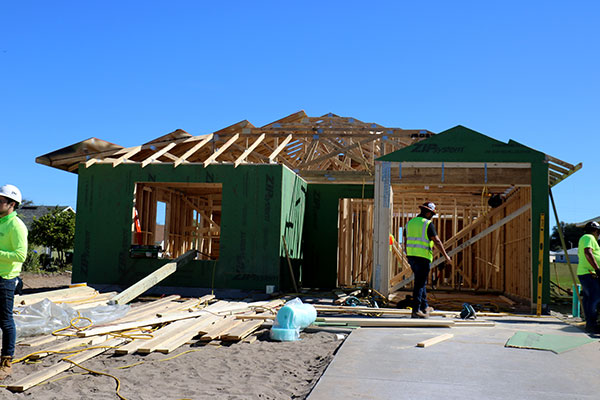 under-construction-house Man wearing polka dot shirt taking a photo on his phone of orange paper with wording on it