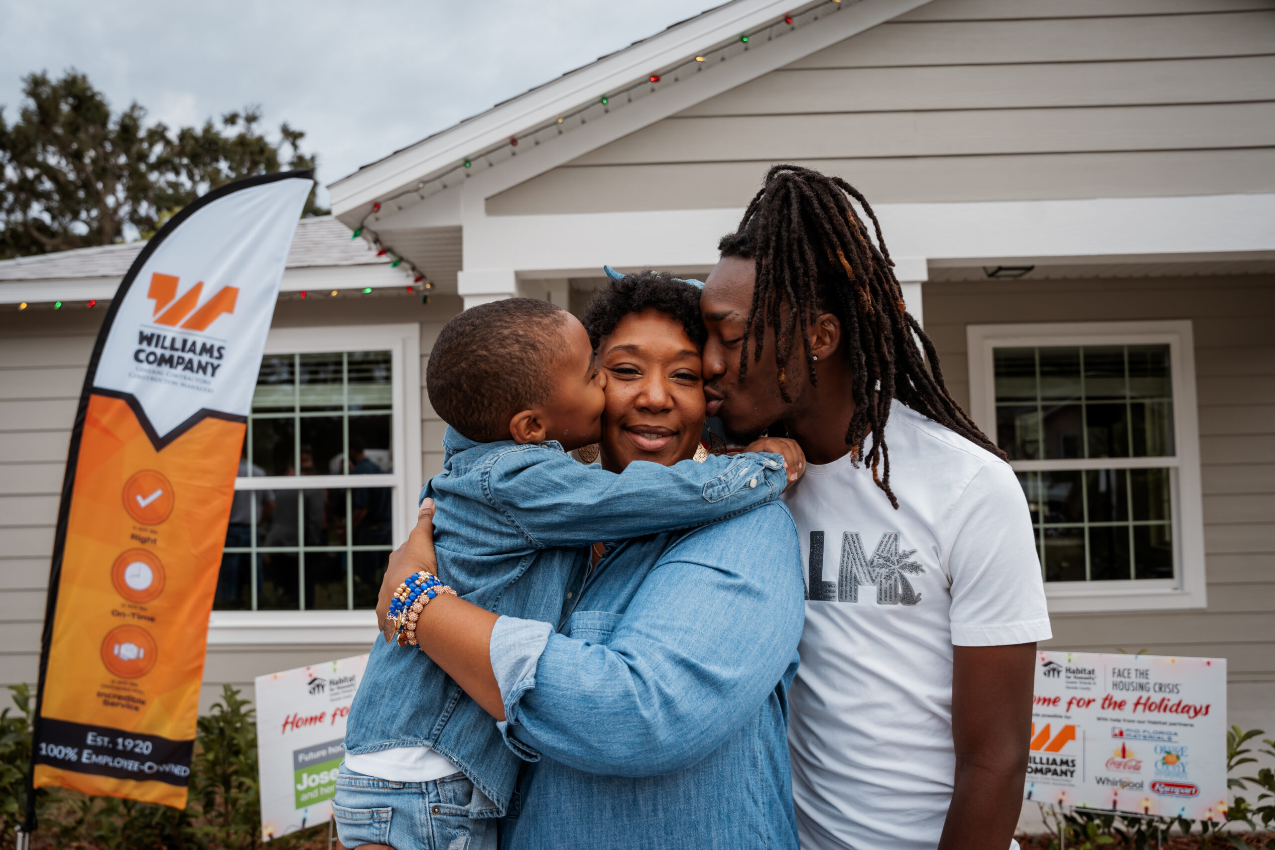 Mujer sonriendo y extendiendo la mano para pintar el revestimiento de una casa con el texto superpuesto &quot;Women Build: Un evento para recaudar fondos&quot; y el logo de Habitat Orlando &amp; Osceola